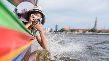 Woman in longtail boat take photo Chao Phraya River in Bangkok.