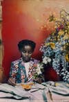 a girl sits at a dinner table next to a big arrangement of flowers