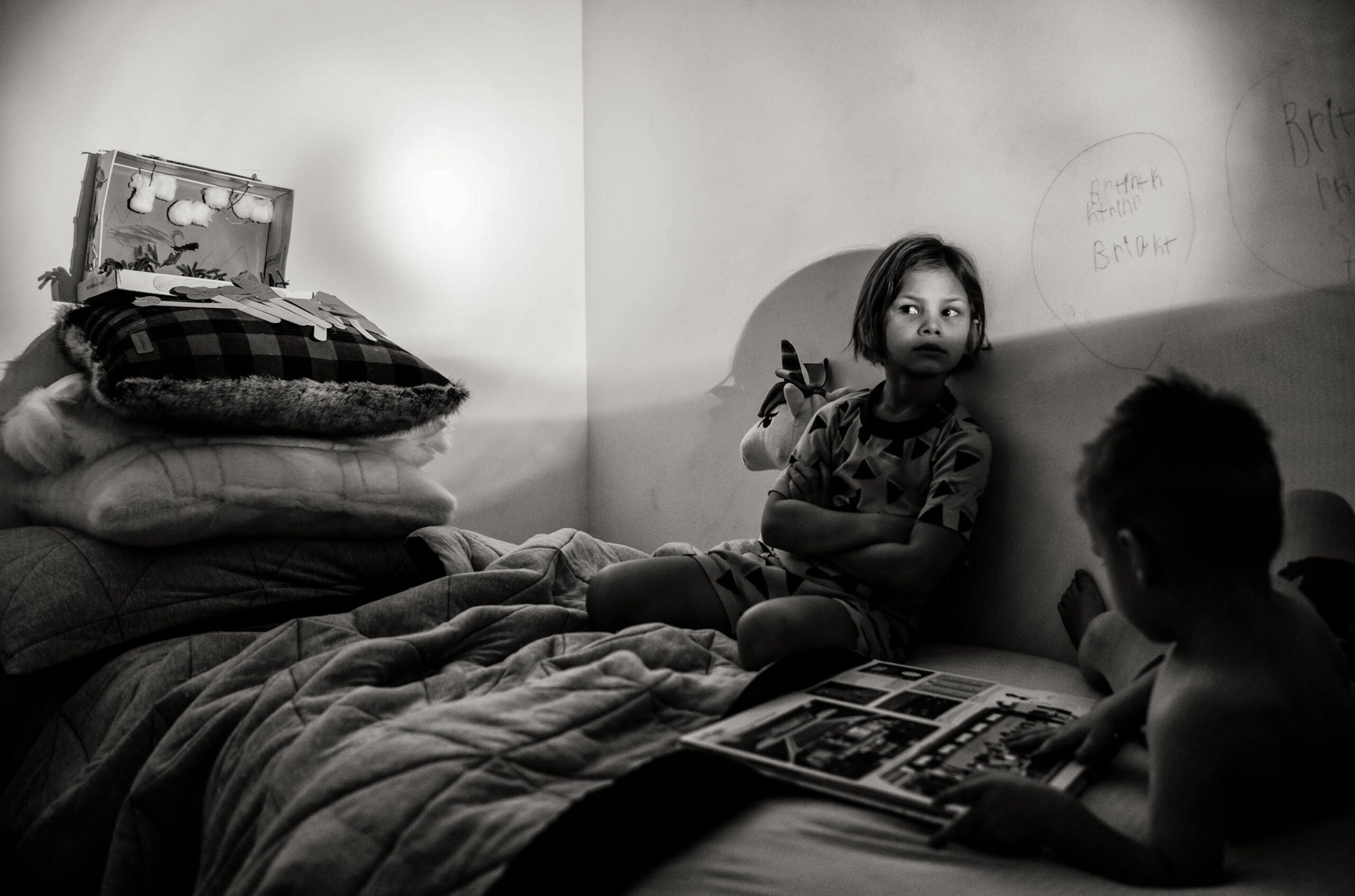 a girl is sitting on a bed in the shadows.  how to photograph children