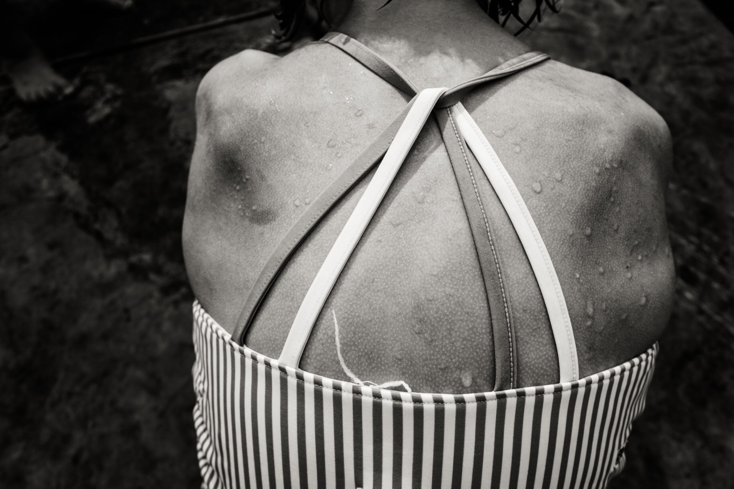 a woman's back with water drops in the sun. black and white photography