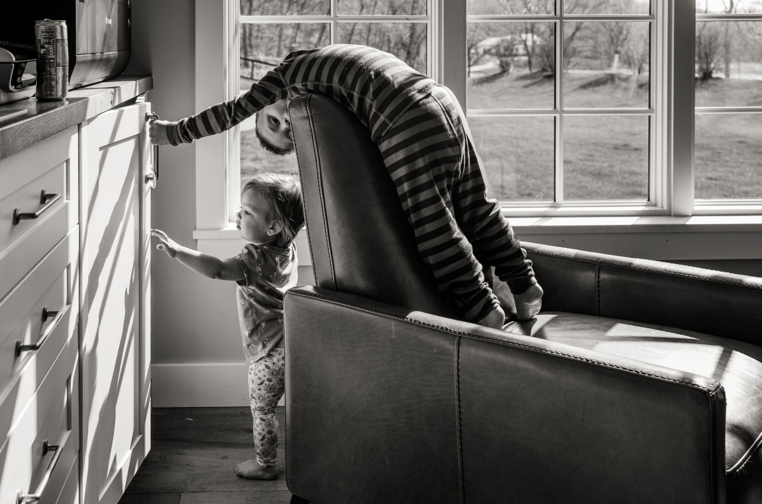 a boy hangs off the back of a couch in pajamas. how to take pictures of children 