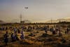 A military transport plane departs overhead as Afghans hoping to leave the country wait outside the Kabul airport on Aug. 23, 2021.