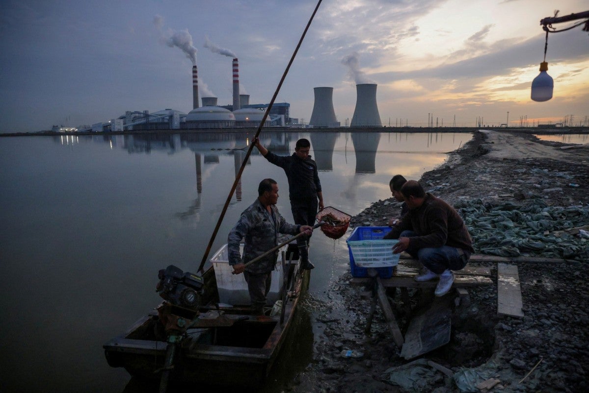 Pescadores trazem suas capturas de um lago em frente a uma usina de energia da State Development and Investment Corporation nos arredores de Tianjin, China, em 14 de outubro de 2021. 