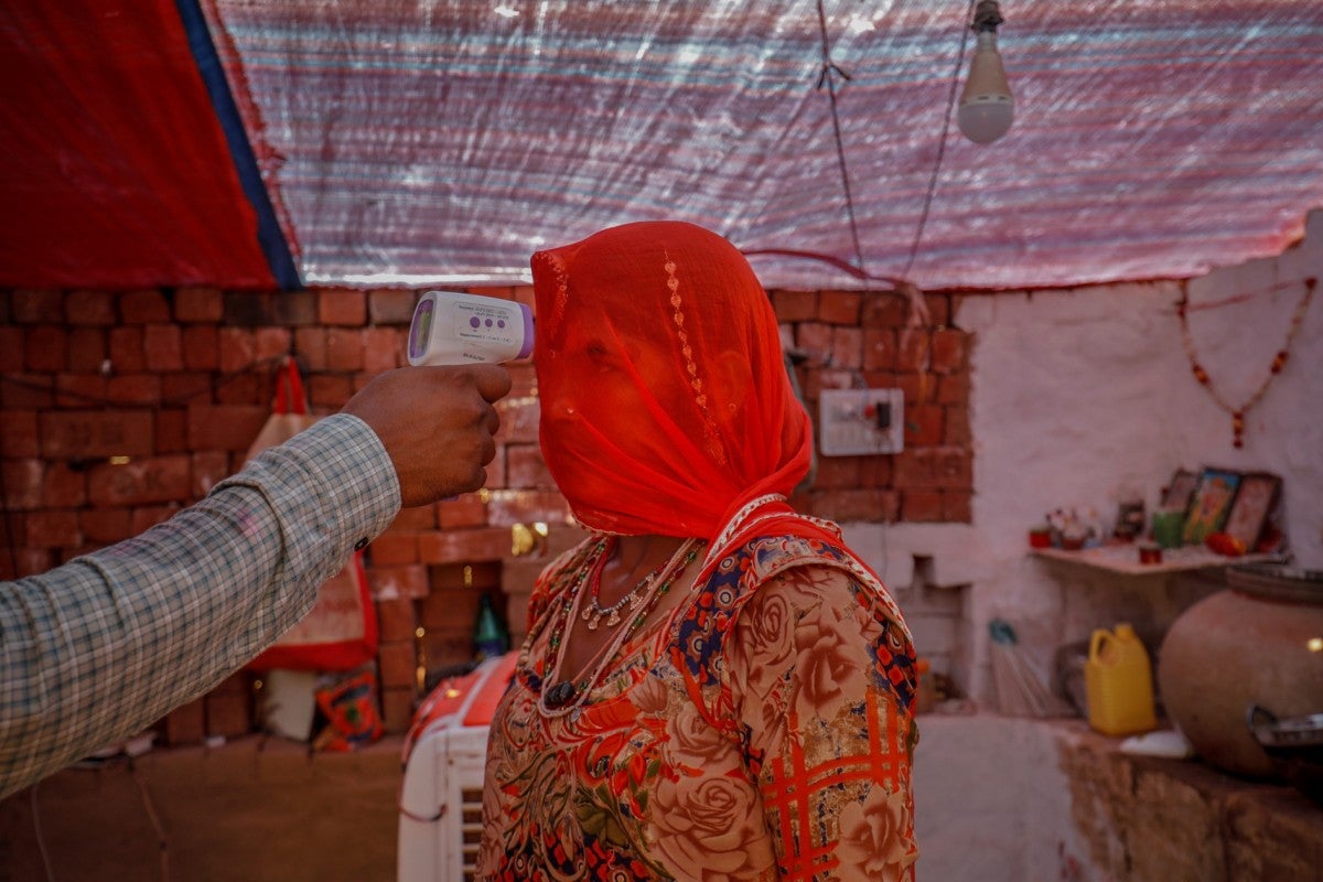 Um profissional de saúde verifica a temperatura de uma mulher dentro de sua cabana durante uma campanha de vacinação contra a doença por coronavírus para trabalhadores em uma olaria na vila de Kavitha, nos arredores de Ahmedabad, Índia, 8 de abril de 2021.