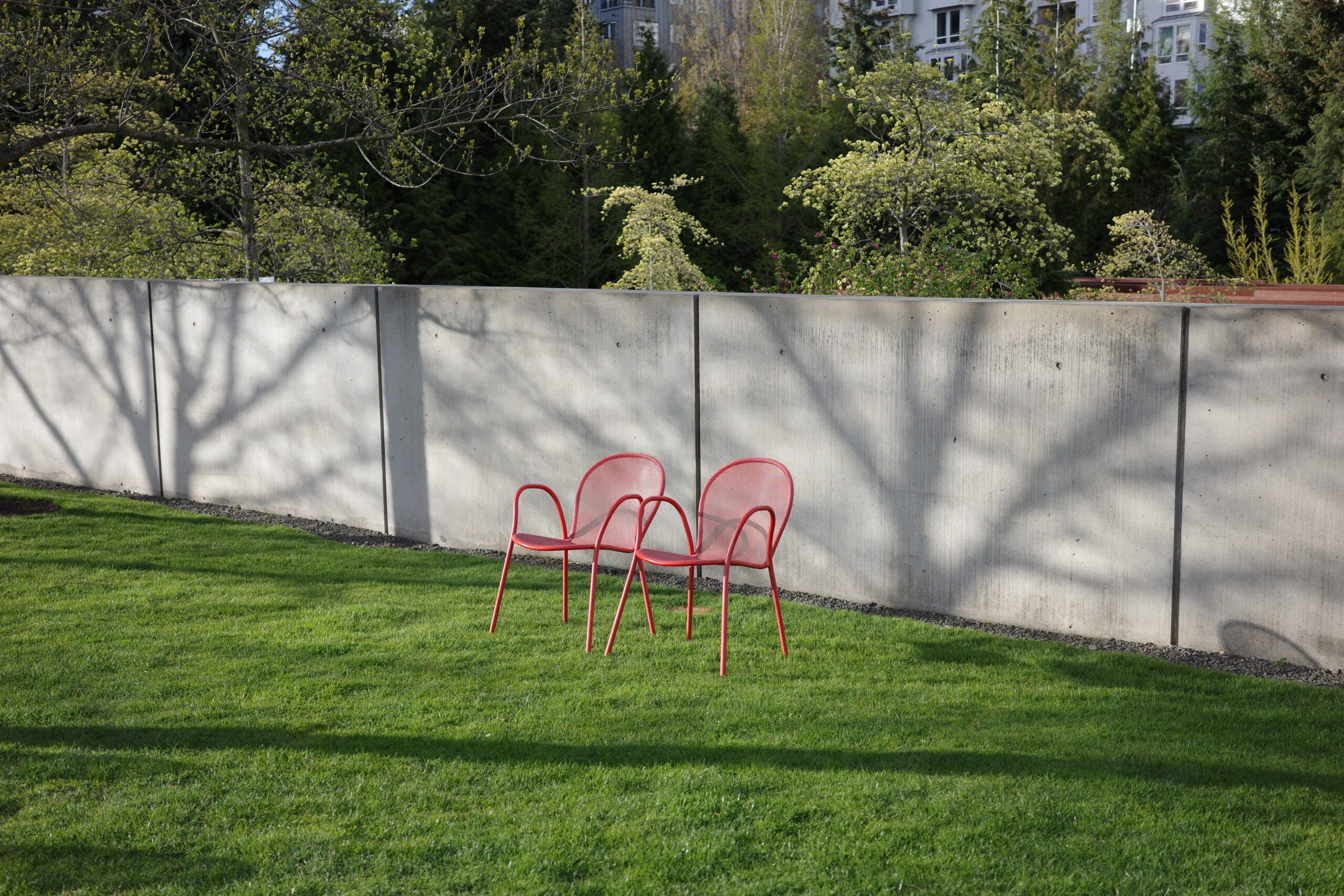 Two empty red chairs on a green lawn.