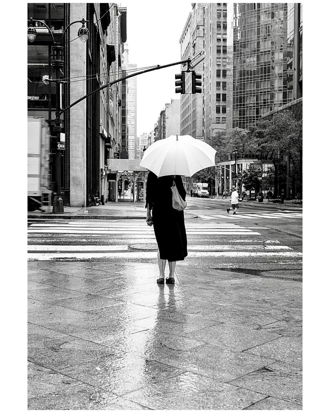 woman stands in rainy new york city with white umbrella