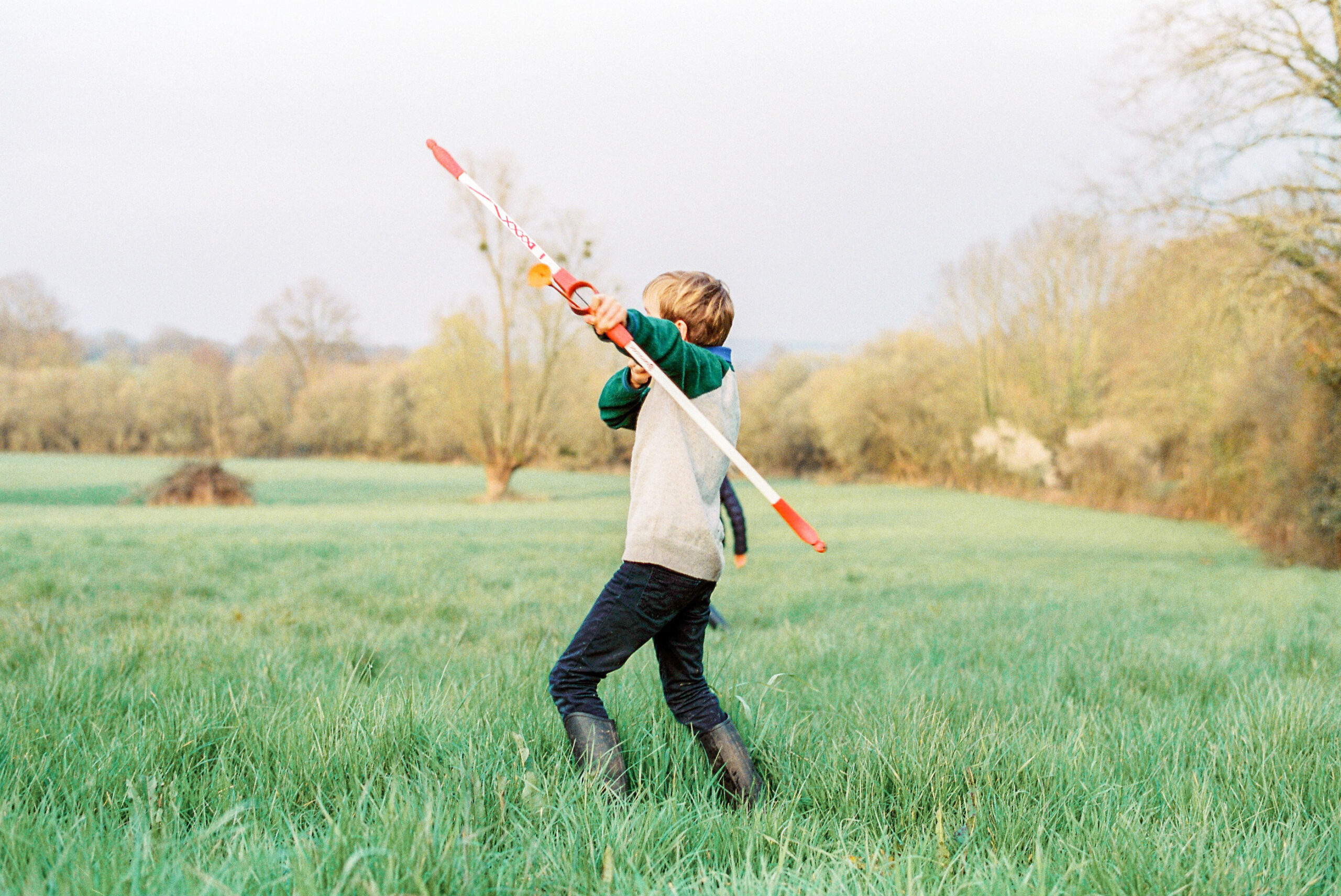boy with rubber bow and arrow in a field decisive moment