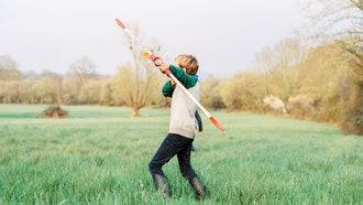 boy with rubber bow and arrow in a field decisive moment