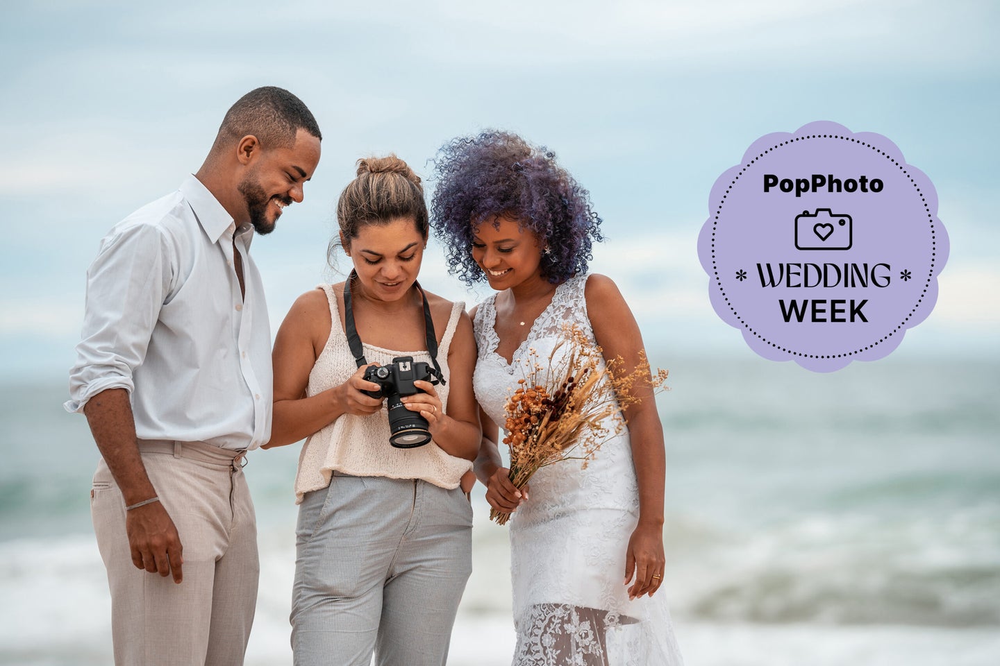 a wedding photographer looking at images with a couple on the beach.