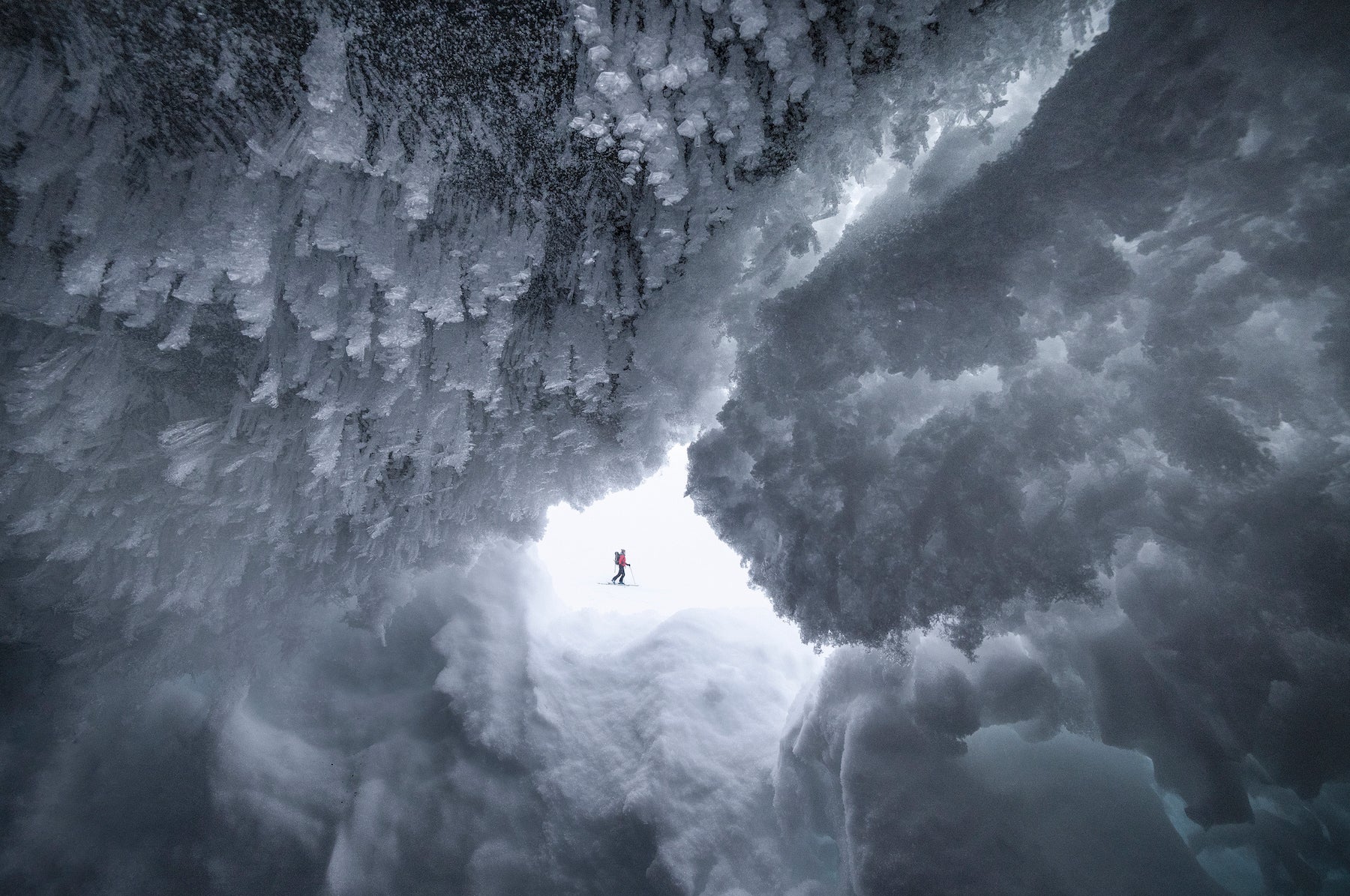 skier seen through a cave of ice