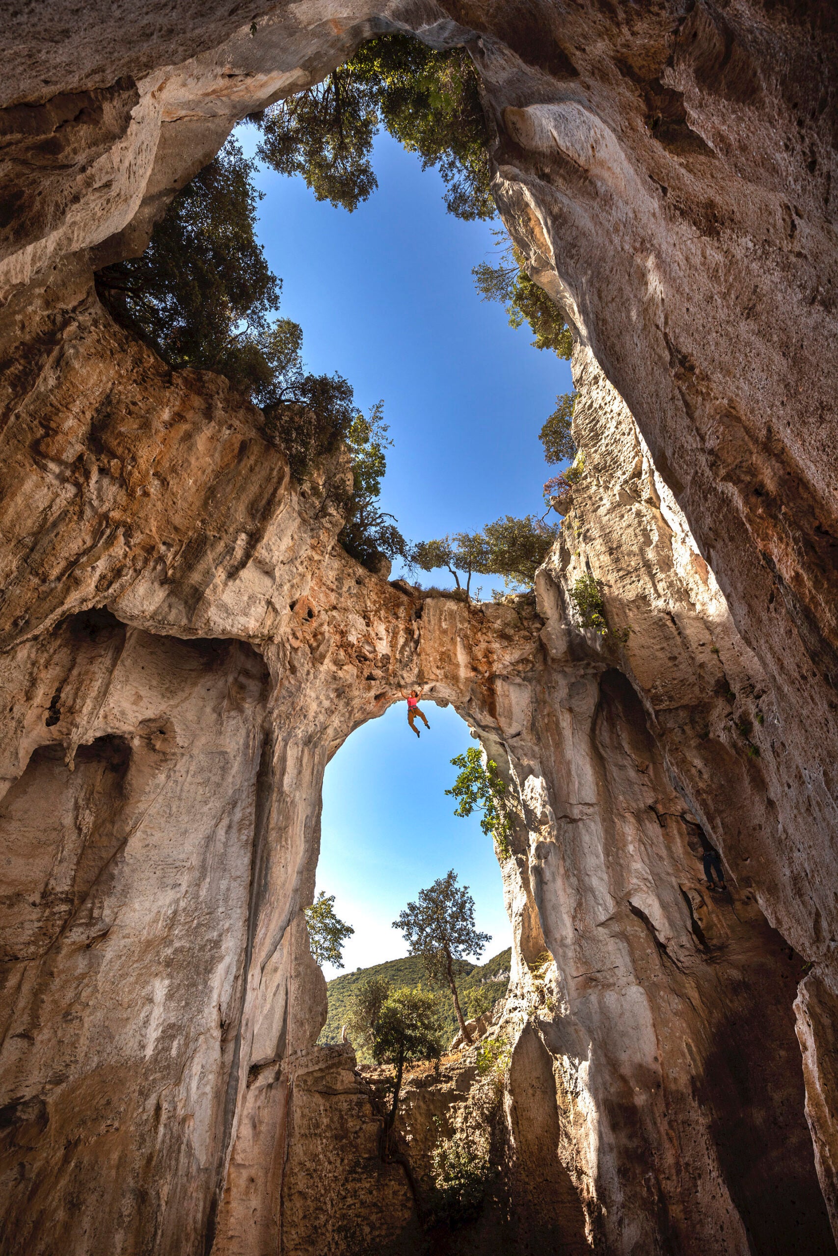 woman dangles from arch cliff