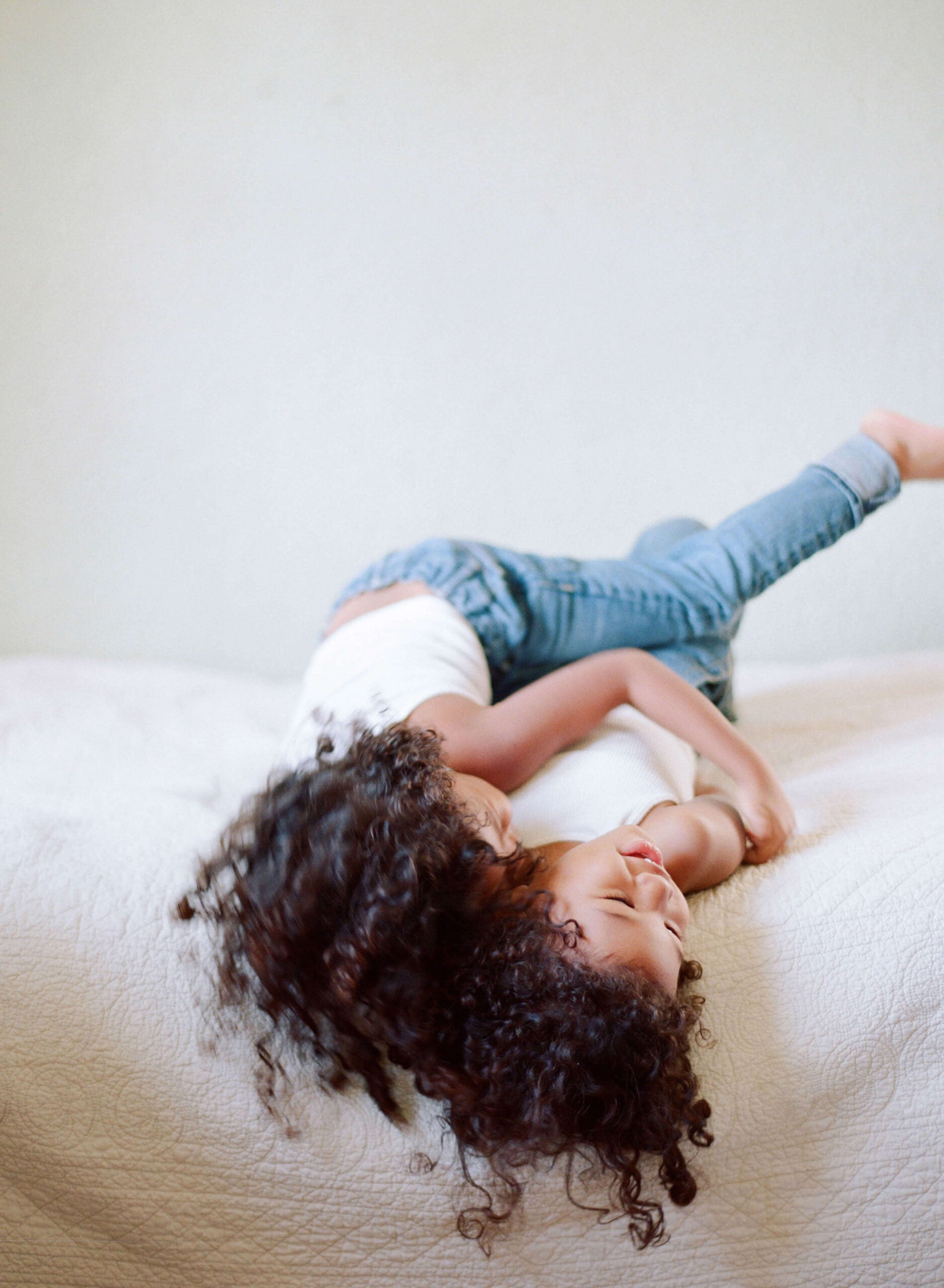 two children play on a bed elizabeth messina