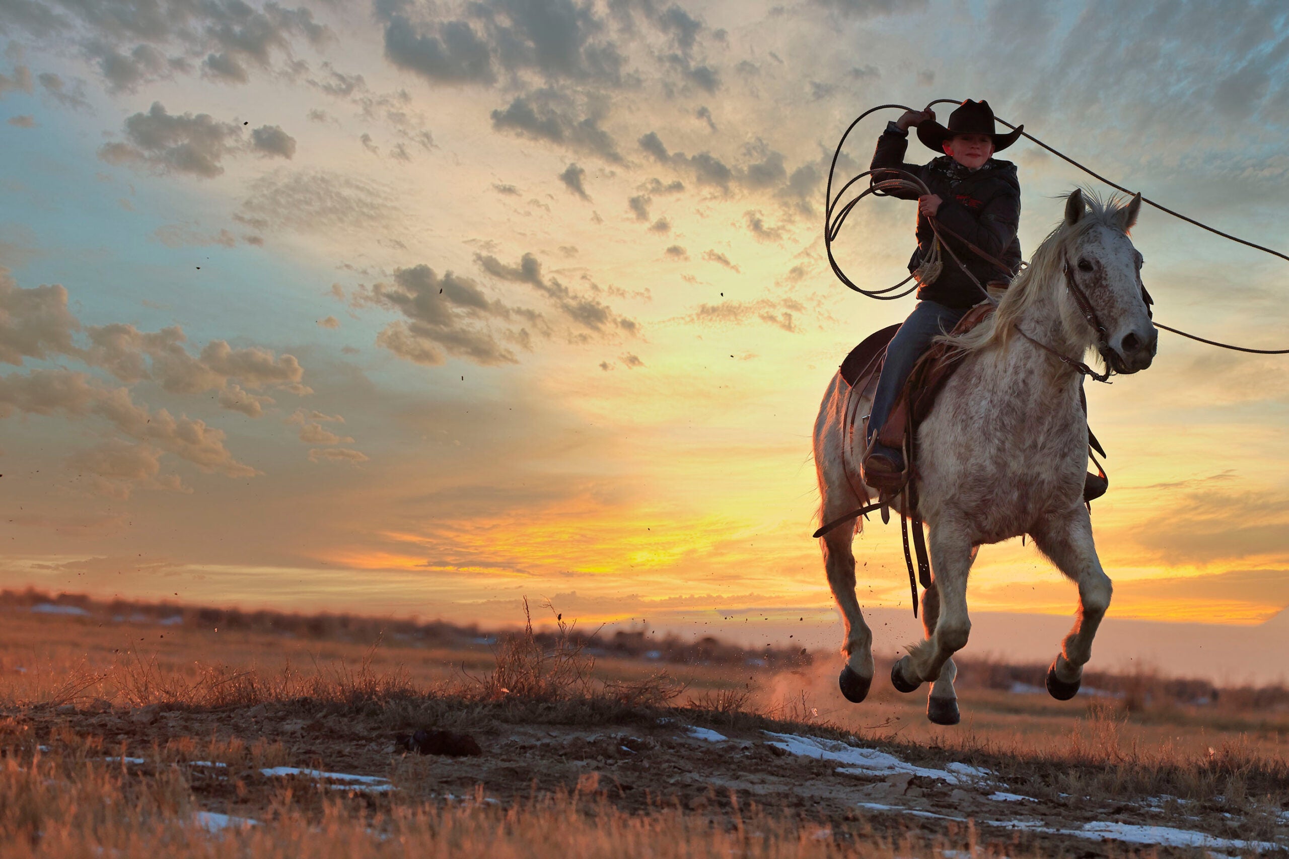 Cow person riding at sunset with lasso.