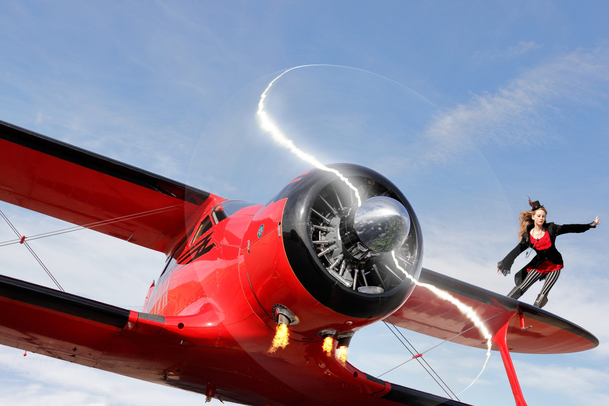 Women in red on wing of red biplane.