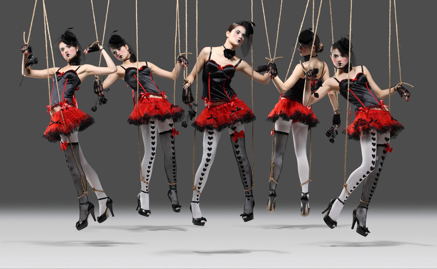 Five dancers held up by puppet strings.