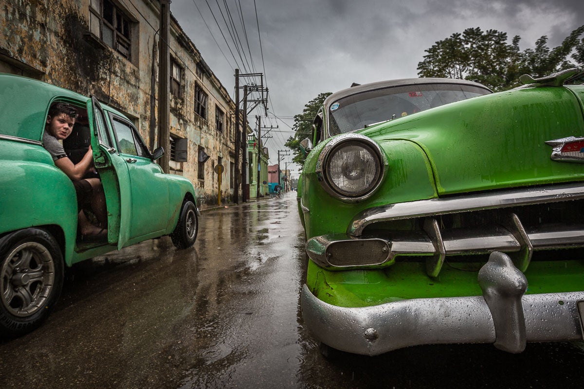 a boy looks out a car door in cuba