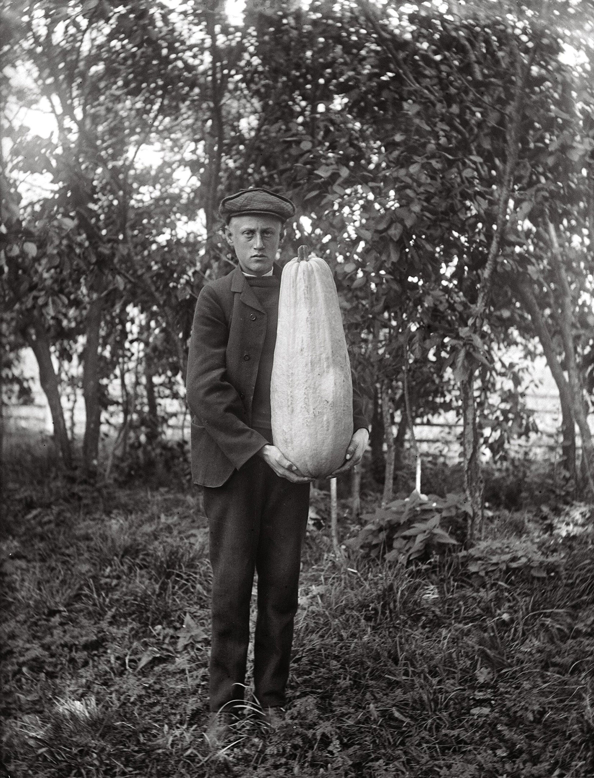 A B&W image of a man with a very large gourd. 
