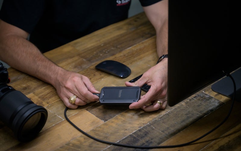 SanDisk Pro-G40 drive plugged in by a hand over a desk