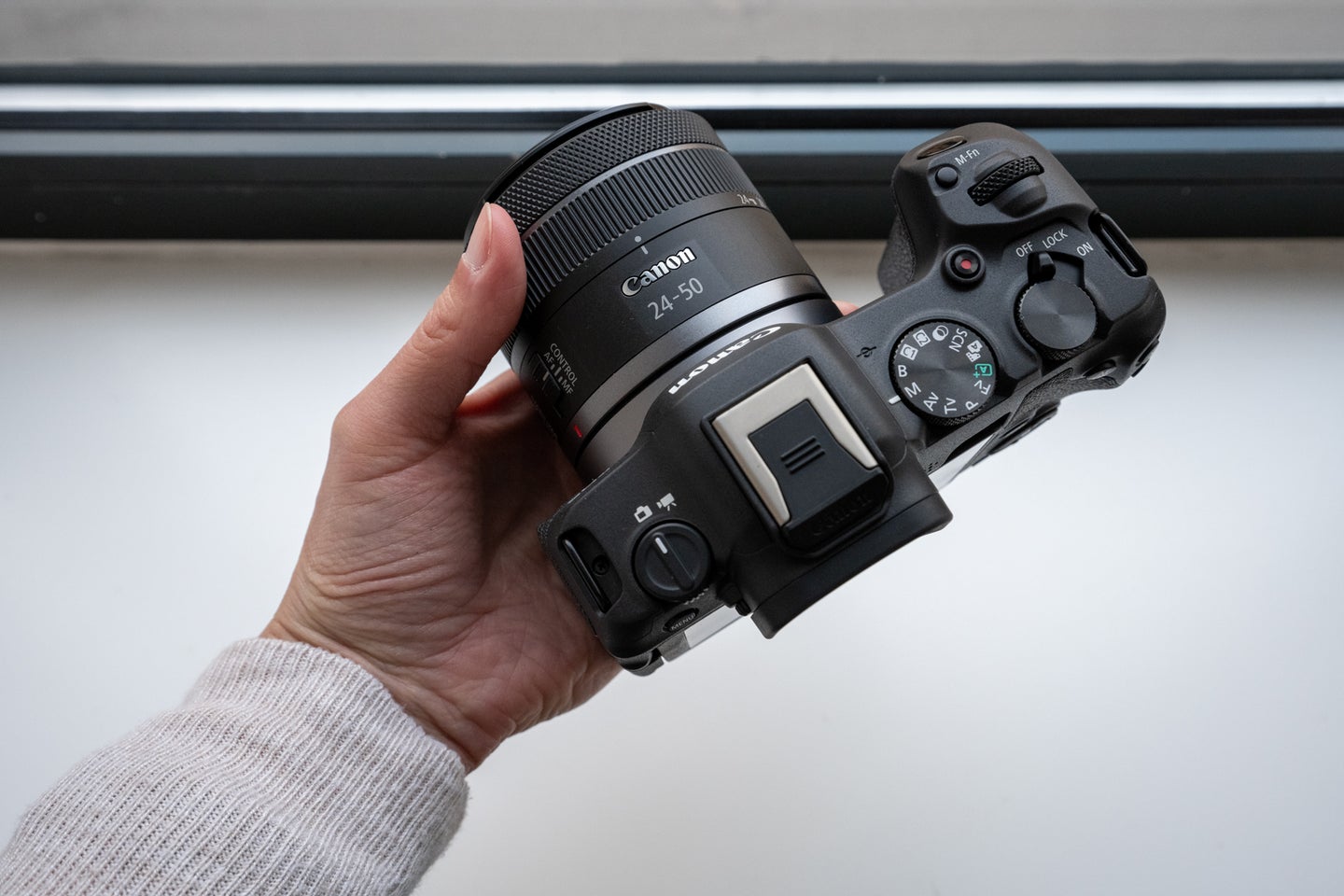 A hand holding the Canon EOS R8 with 24-50mm lens