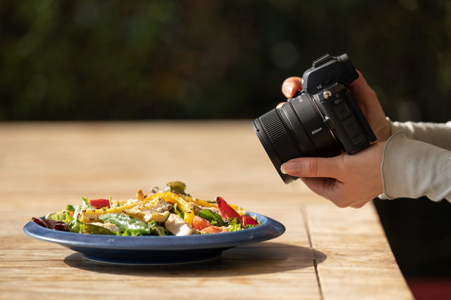 The NIKKOR Z DX 12-28mm f/3.5-6.5 PZ VR on a Nikon camera being held to photograph food