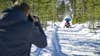 A photographer takes a photo of a snowmobiler in a forest using the Nikon Z9