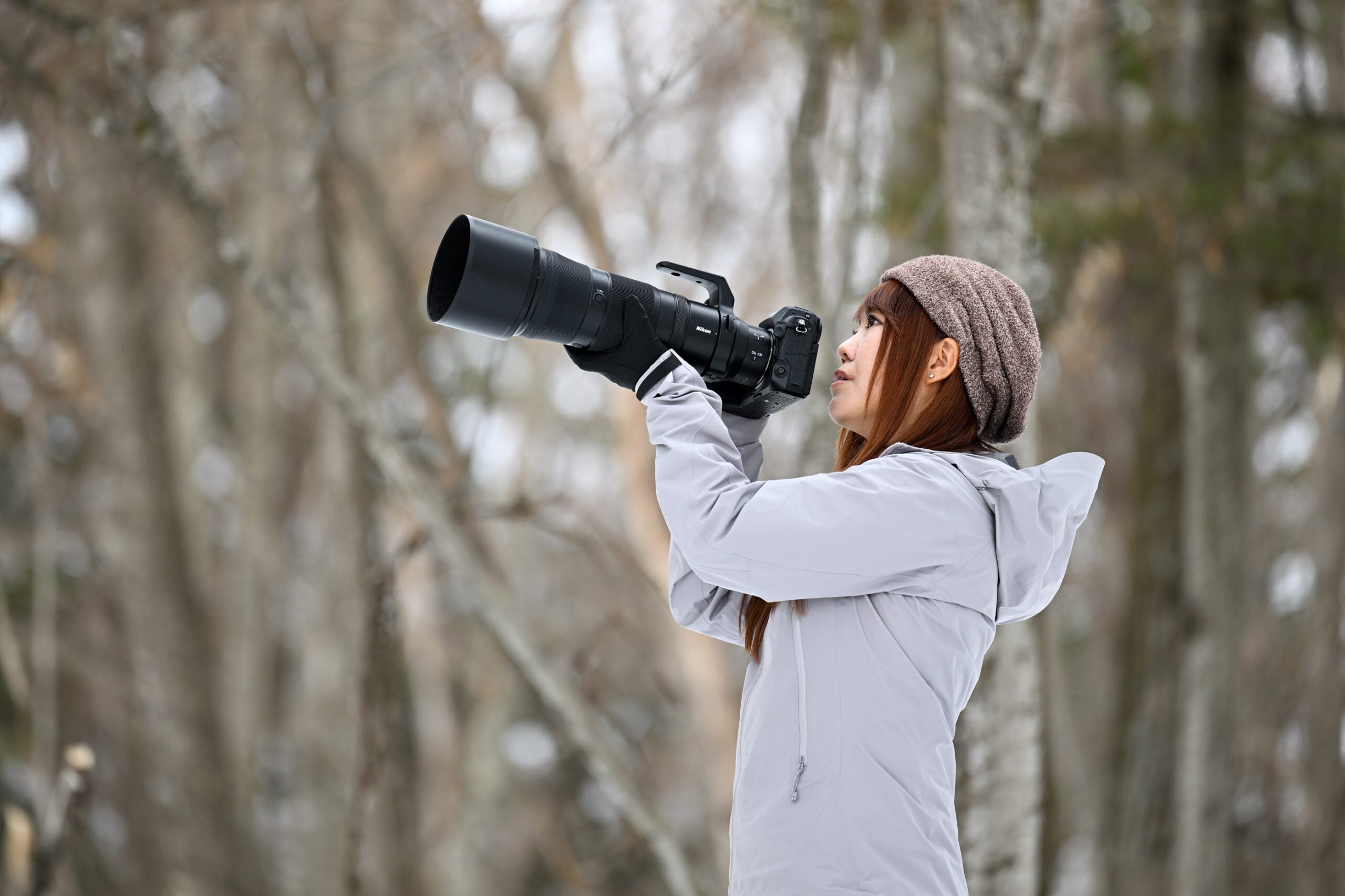 A woman holds the Nikon NIKKOR Z 180-600mm f/5.6-6.3 VR lens.