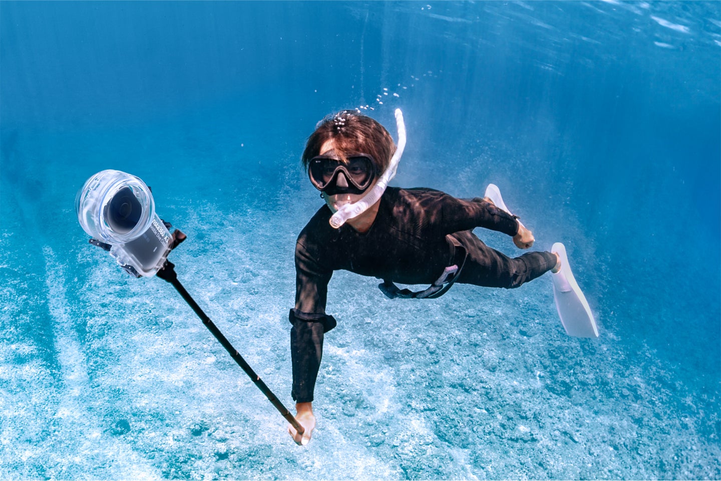 A person snorkels with the Insta360 X3 in the invisible dive case