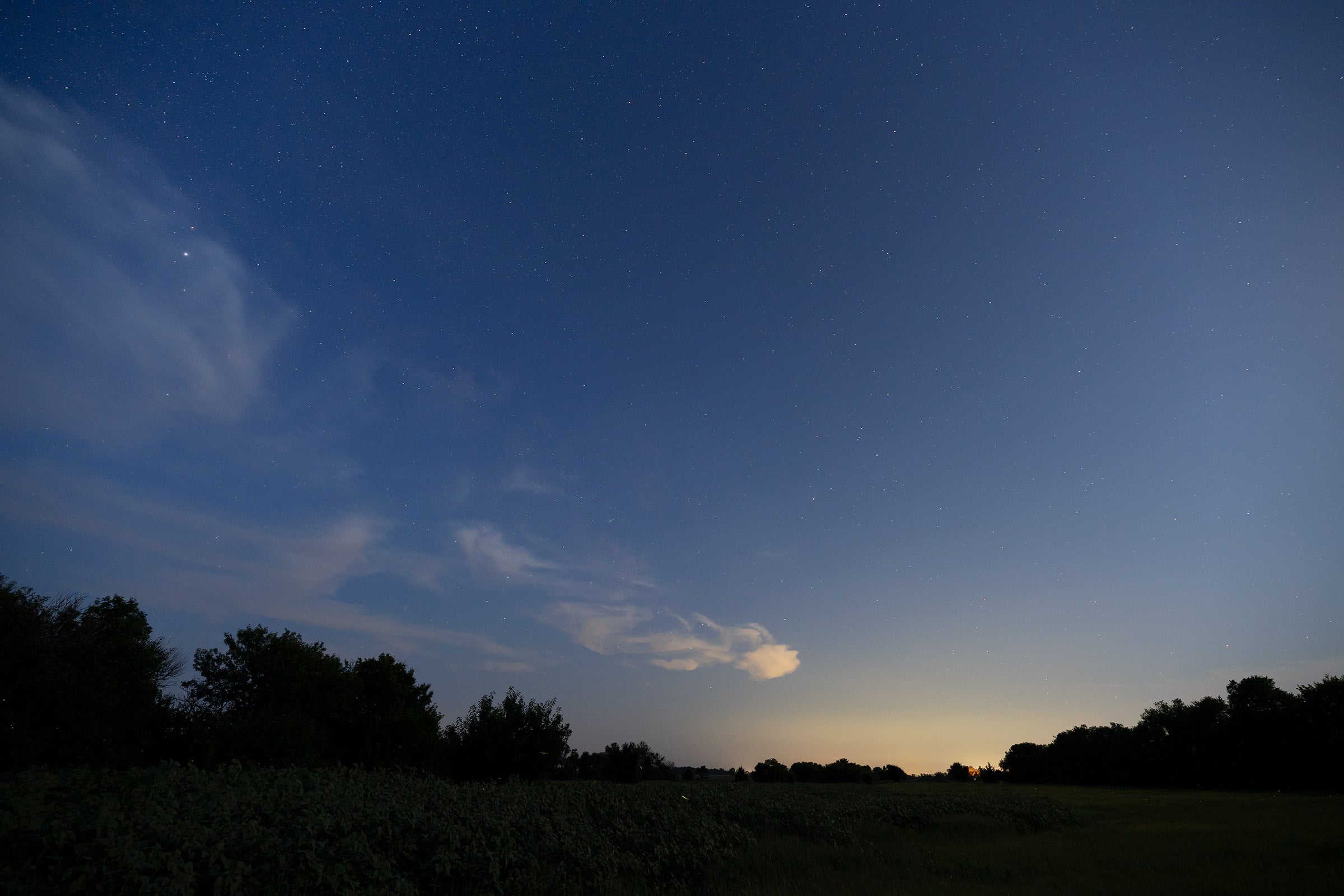 a night sky with city glow and some swirly clouds