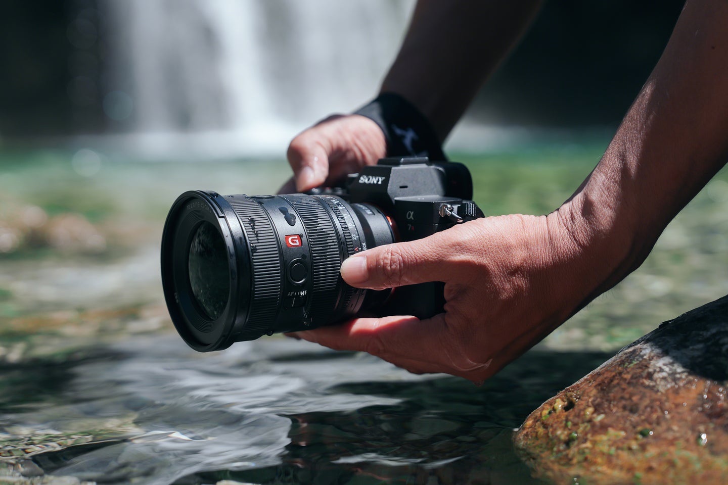 The Sony 16-35mm f/2.8 GM II on a Sony camera being held in front of a waterfall