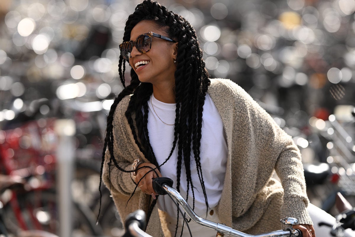 A photo of a Black woman on a bike with a field of bokeh behind her.